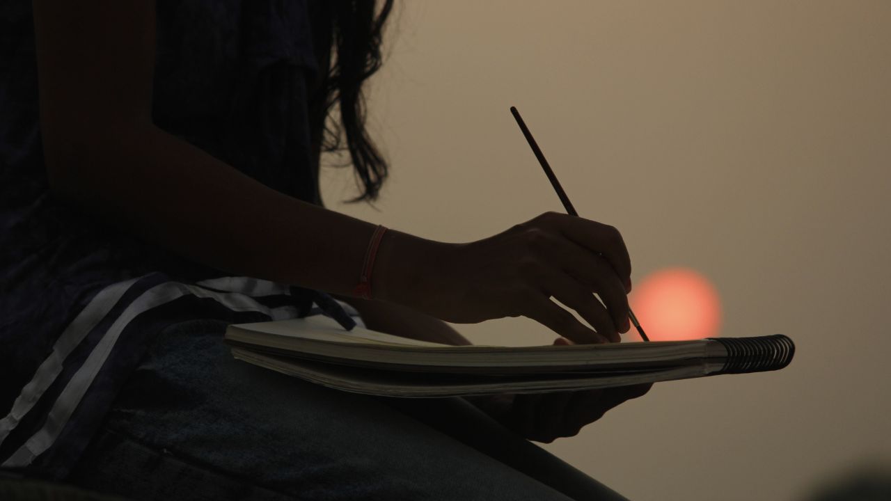 silhouette of someone drawing at sunset